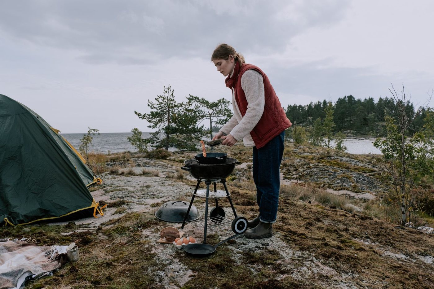 Barbecue portable installé près d'une tente au bord de l'eau