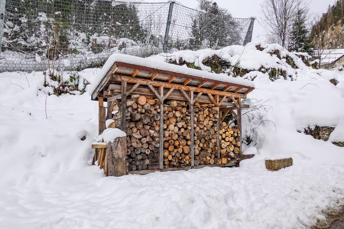 Bûches empilées sous un abri en bois ouvert en hiver
